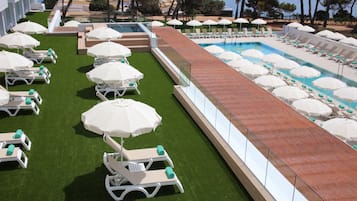 Un área de piscina en la azotea con múltiples tumbonas y sombrillas, rodeada por una barandilla de cristal.