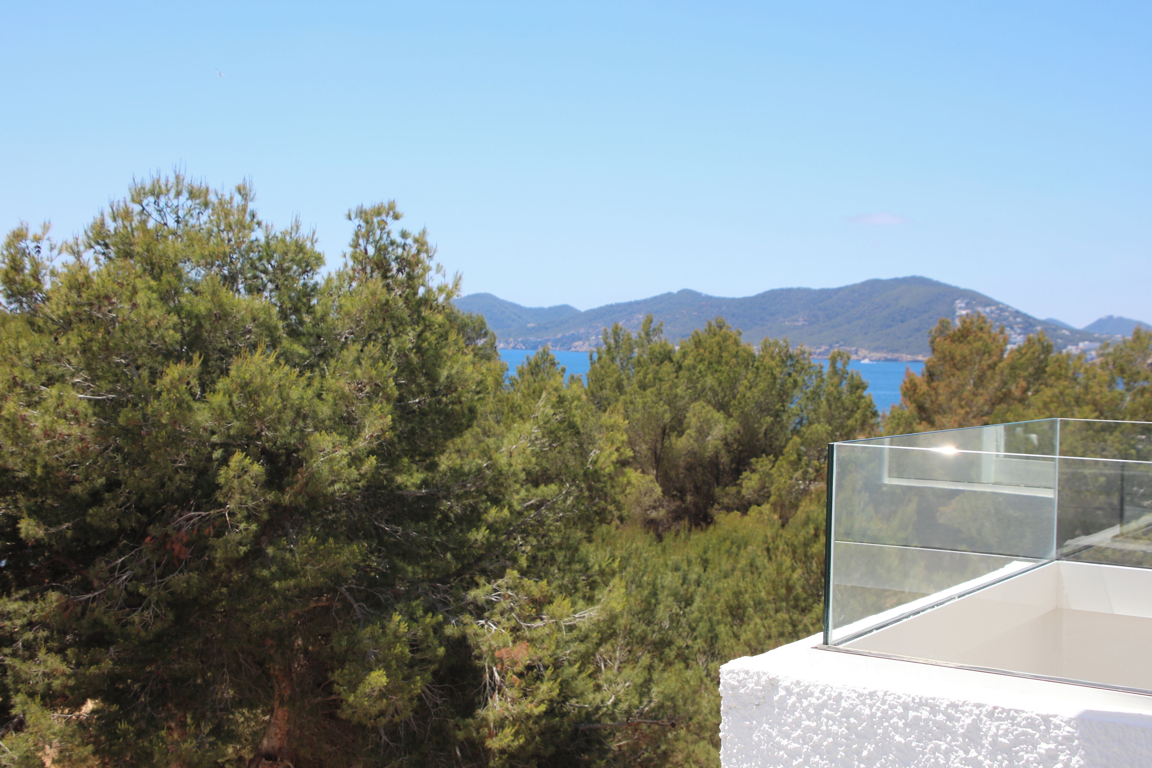 A balcony with a clear view of a mountainous landscape and a body of water.