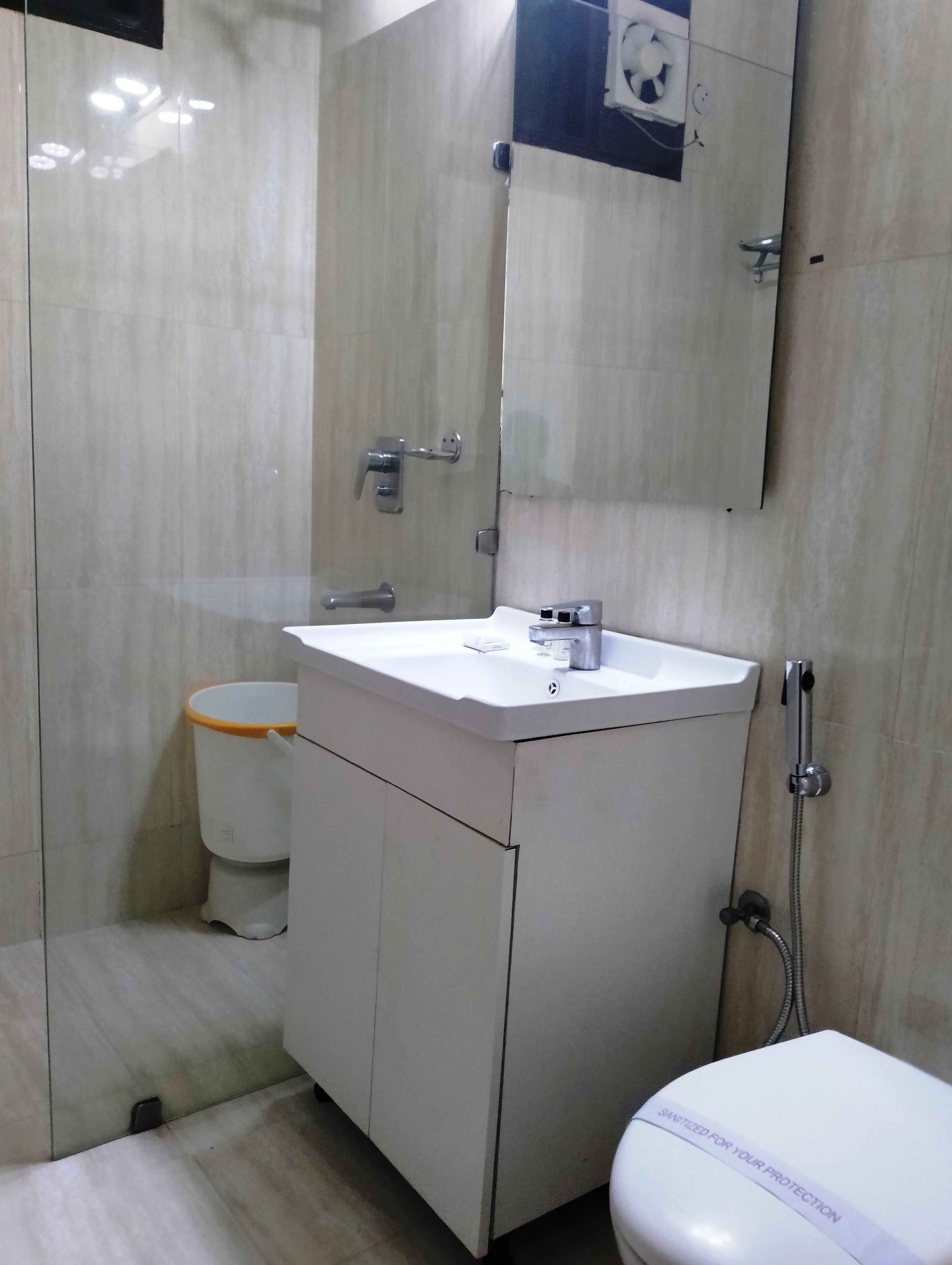 A modern bathroom with a white sink, mirror, and toilet.