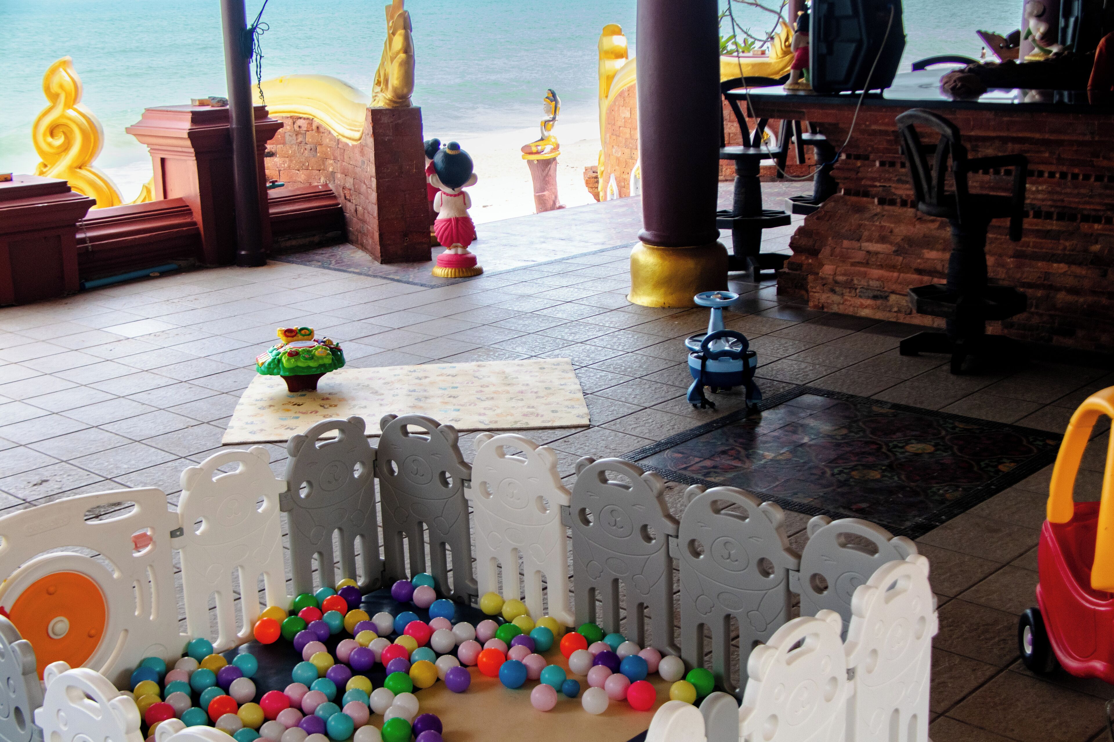 Zona de juegos para niños con piscina de pelotas, una mesa pequeña con juguete y vistas a la playa.
