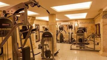 Une salle de sport équipée de divers appareils d’entraînement, notamment un vélo elliptique StarTrac et une machine Smith.