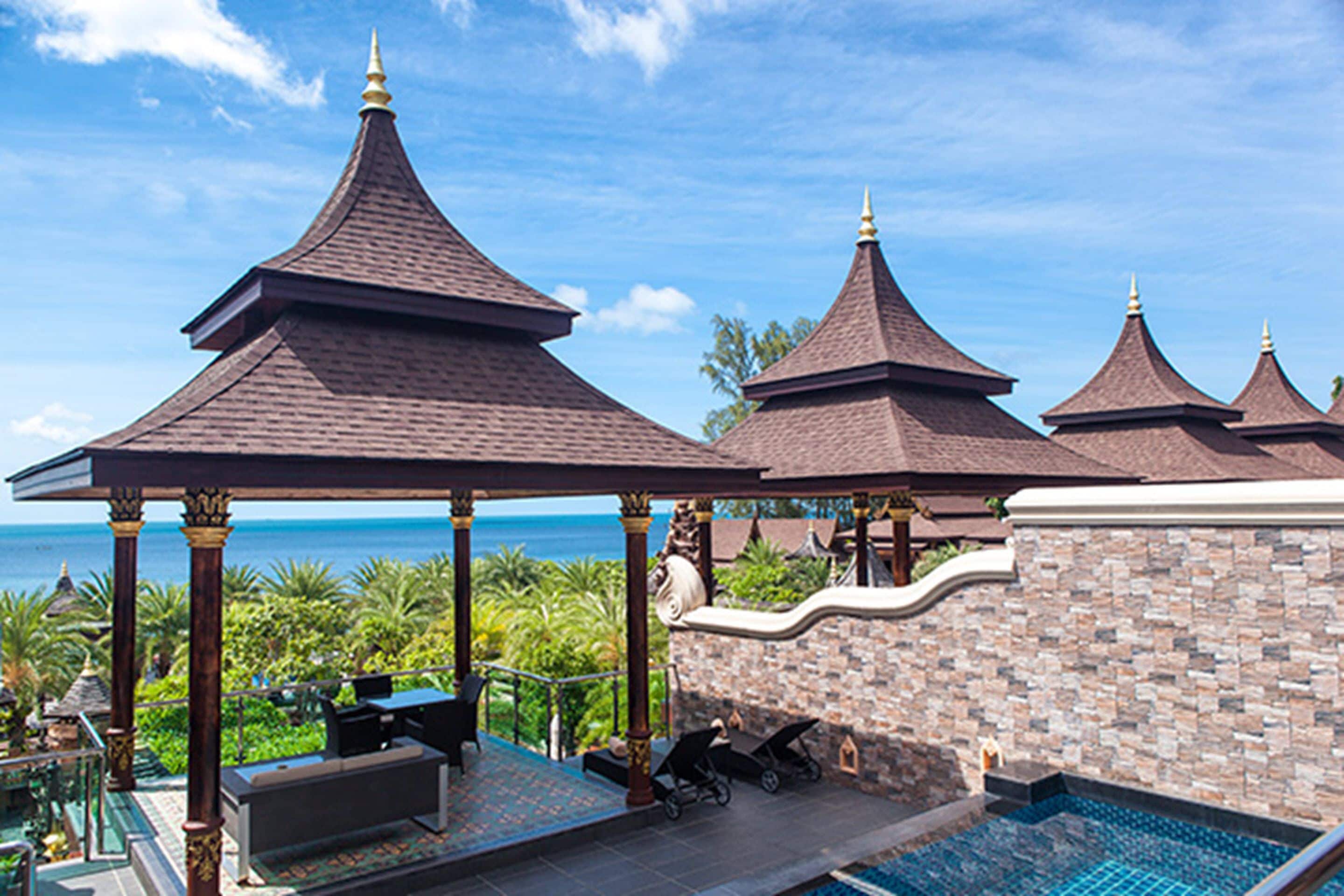 A resort with a pool, outdoor seating, and a view of the ocean.