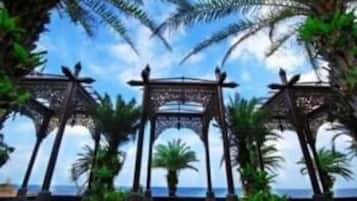 A view of a beachside walkway with palm trees and a clear sky.