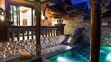 An indoor pool area with stone walls, a bench, and a staircase leading to a higher level.