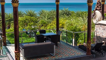 Un espacio al aire libre cubierto con vistas al océano, que incluye una mesa y sillas, un sofá y un suelo con diseño.