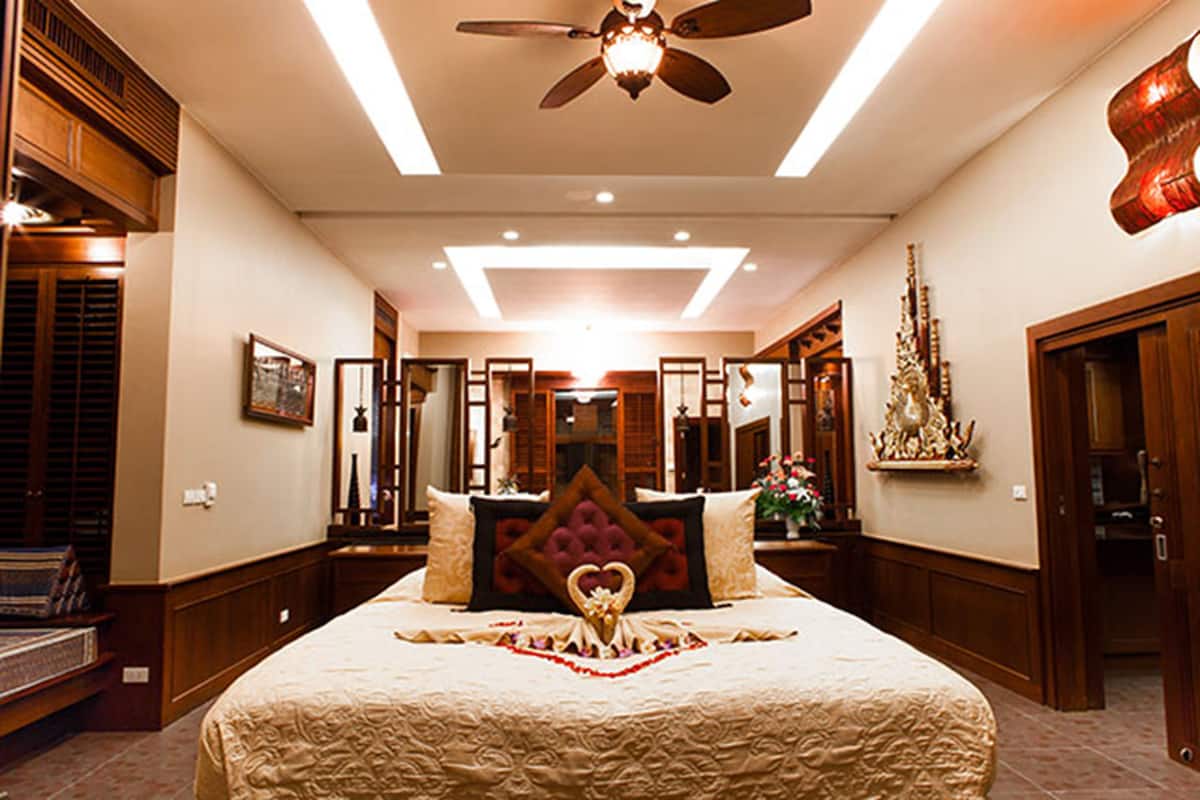 A spacious bedroom with a large bed, a ceiling fan, and a decorative wall piece.