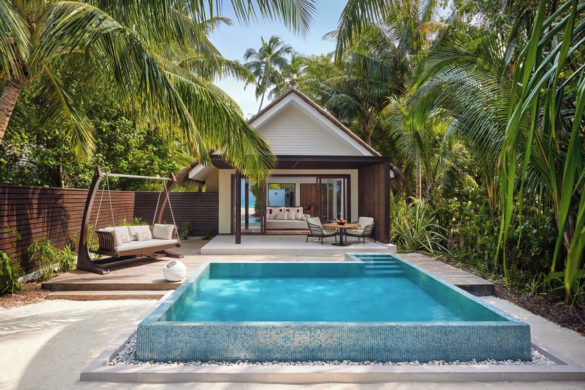 Ein modernes Haus mit Swimmingpool, einer Hängematte und einer Terrassenanlage mit Gartenmöbeln.
