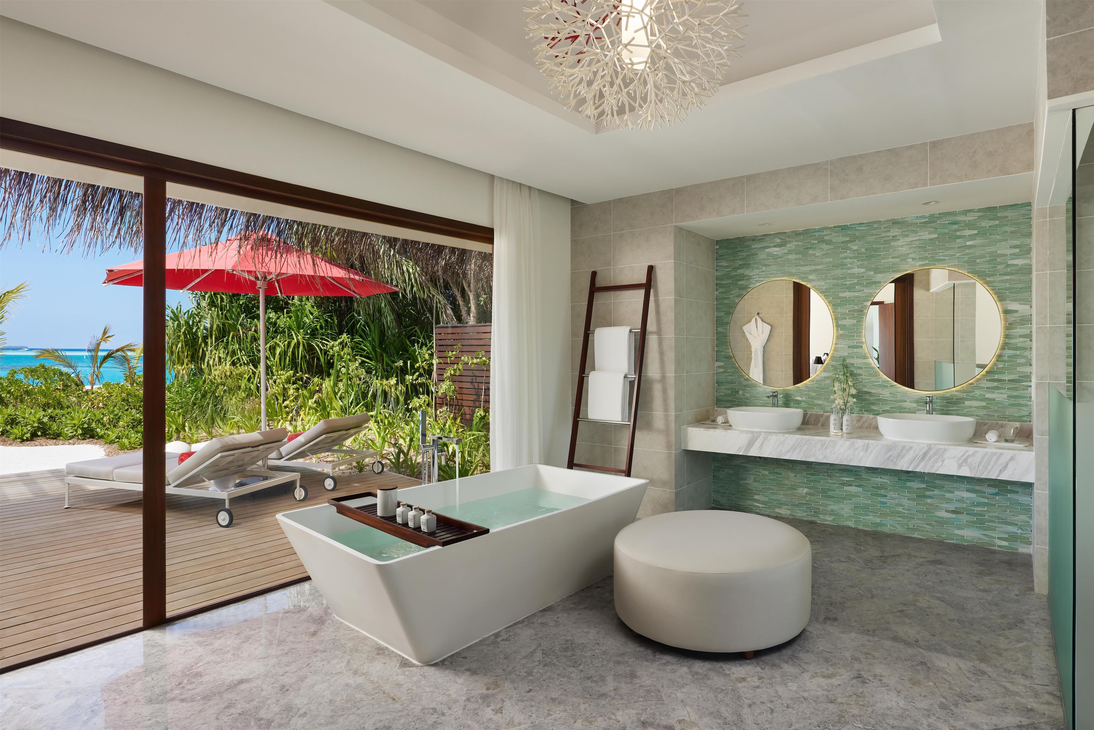 A modern bathroom with a freestanding bathtub, a round seating area, and a large mirror with two round mirrors above the sink.
