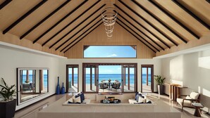 A spacious living area with a high ceiling, large windows, and a view of the ocean.