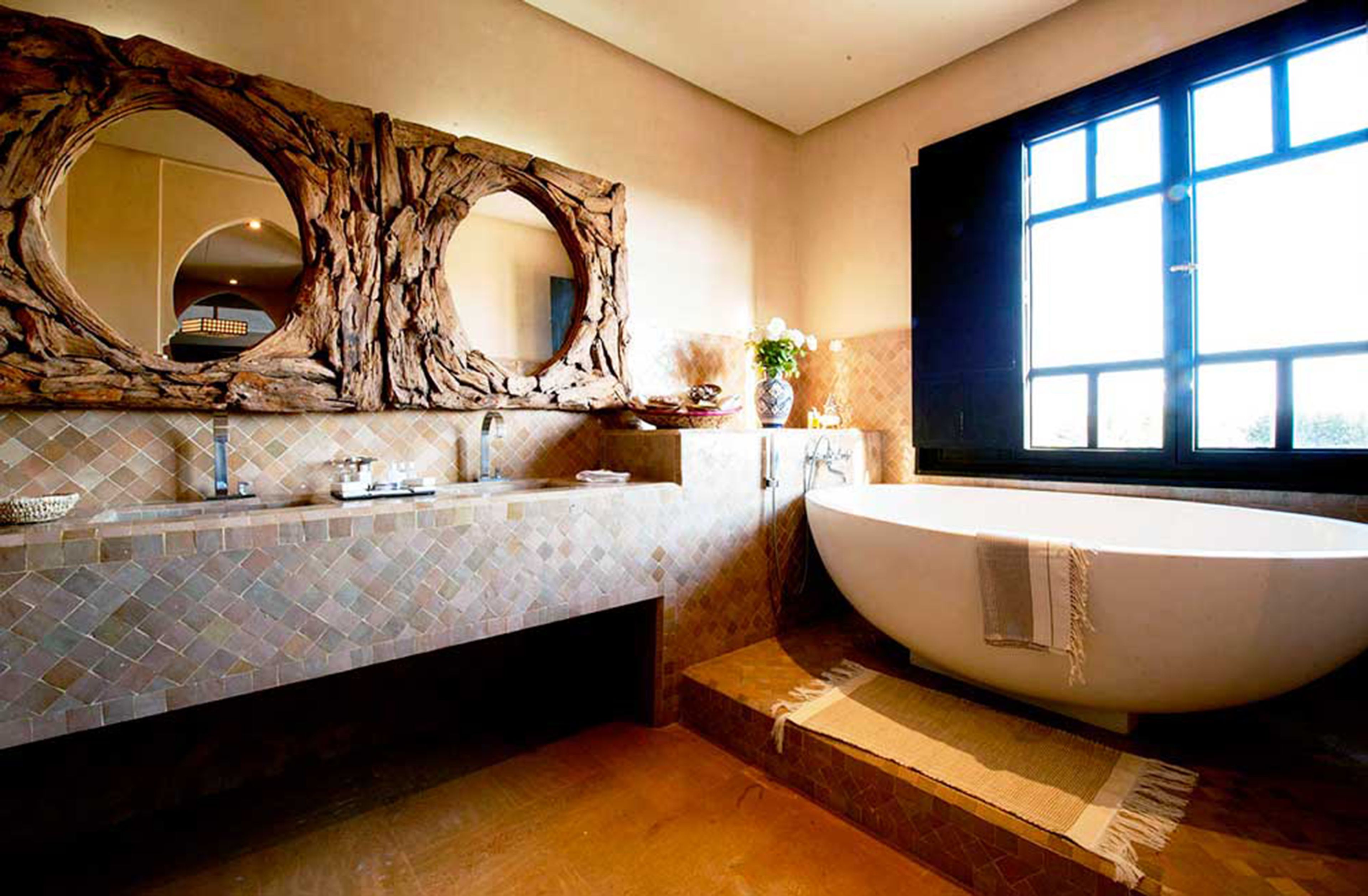 Ein modernes Badezimmer mit einer freistehenden Badewanne, einem großen Spiegel mit natürlichem Holzrahmen und einer gefliesten Rückwand.