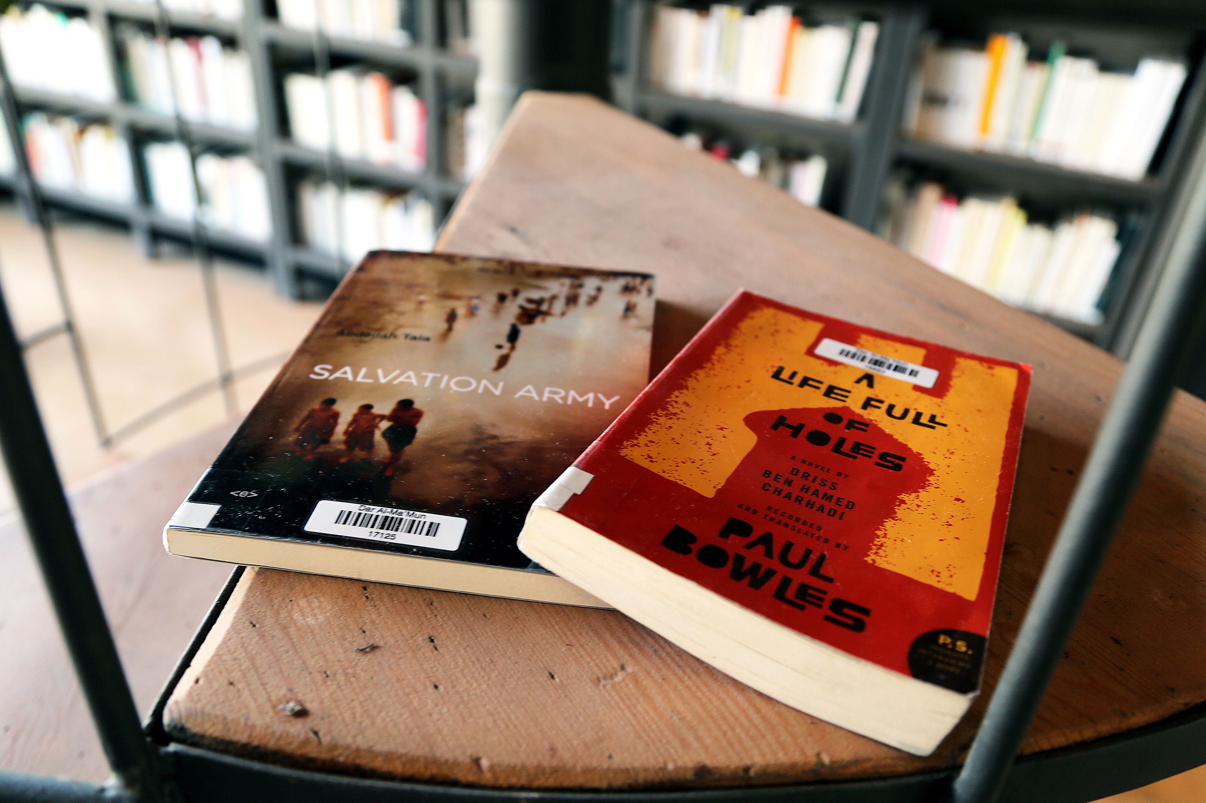 Two books on a wooden table in a library.