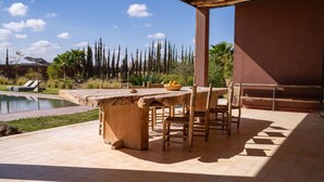 An outdoor patio with a stone table, chairs, and a pool. - Fellah Hotel (Marrakech)
