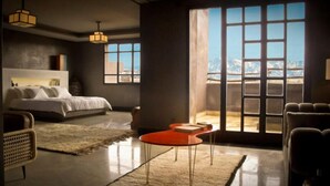 A modern bedroom with a large bed, a red side table, and a view of a snowy landscape through a large window. - Fellah Hotel (Marrakech)