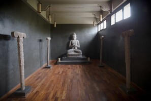 A statue in a corridor with wooden flooring and columns on either side.