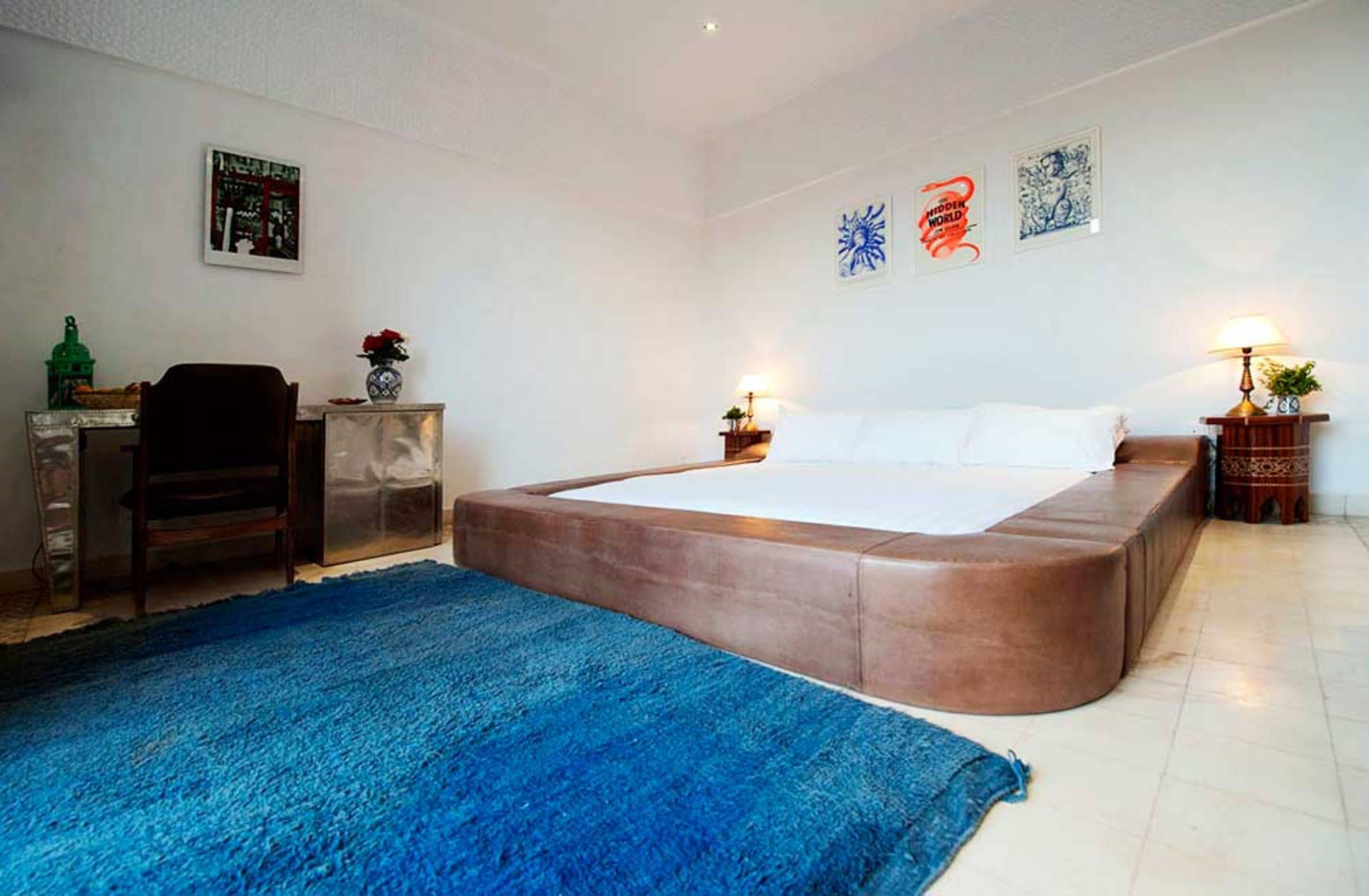 Un dormitorio con una cama grande, un escritorio, una silla y un tapete azul.