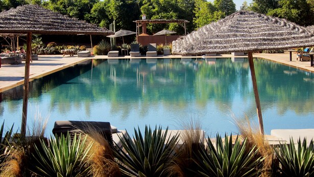 A pool area with lounge chairs and thatched umbrellas. - Fellah Hotel (Marrakech)