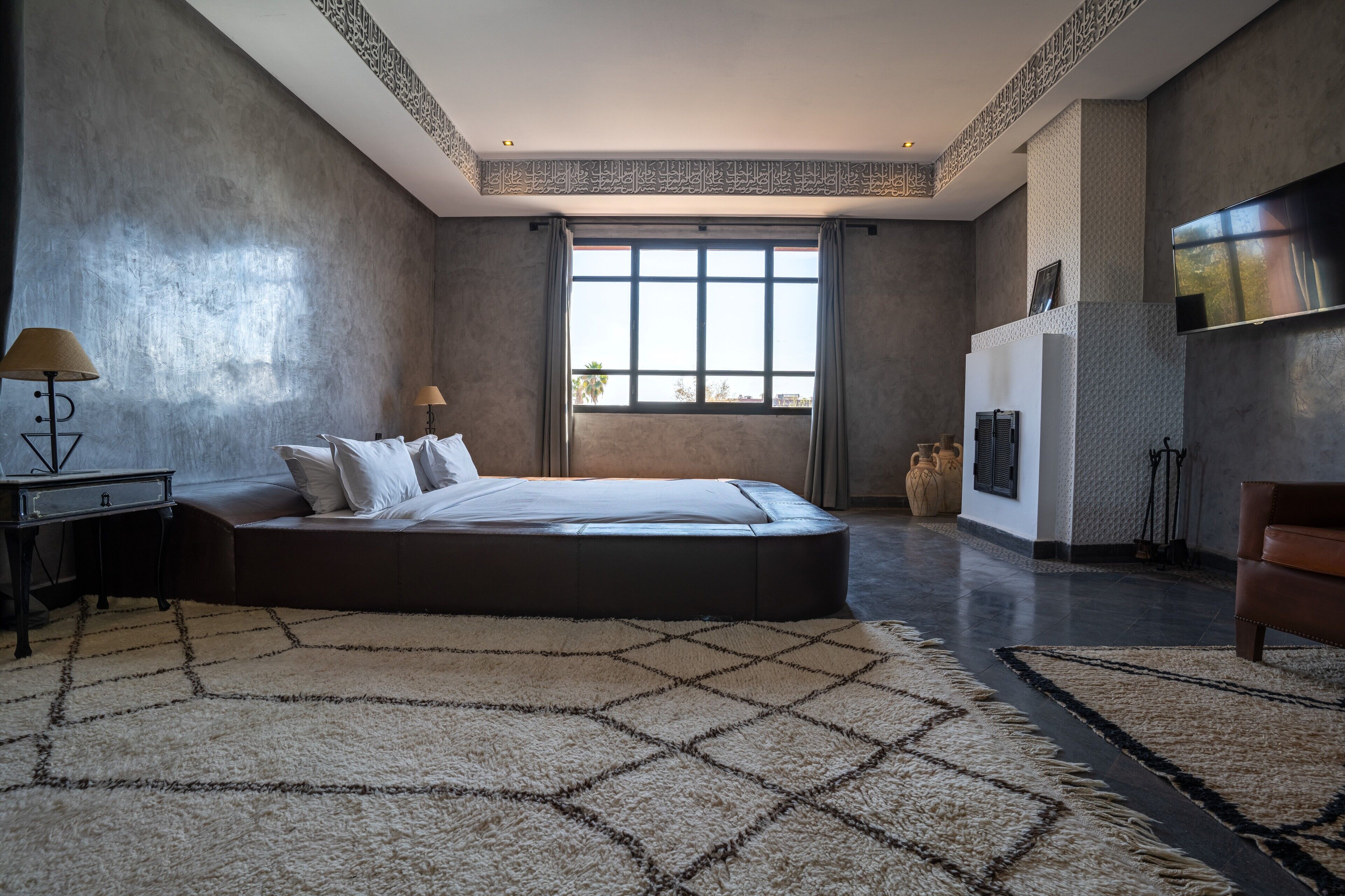 Quarto moderno com uma cama grande, televisão de tela plana e vista da cidade através de amplas janelas.