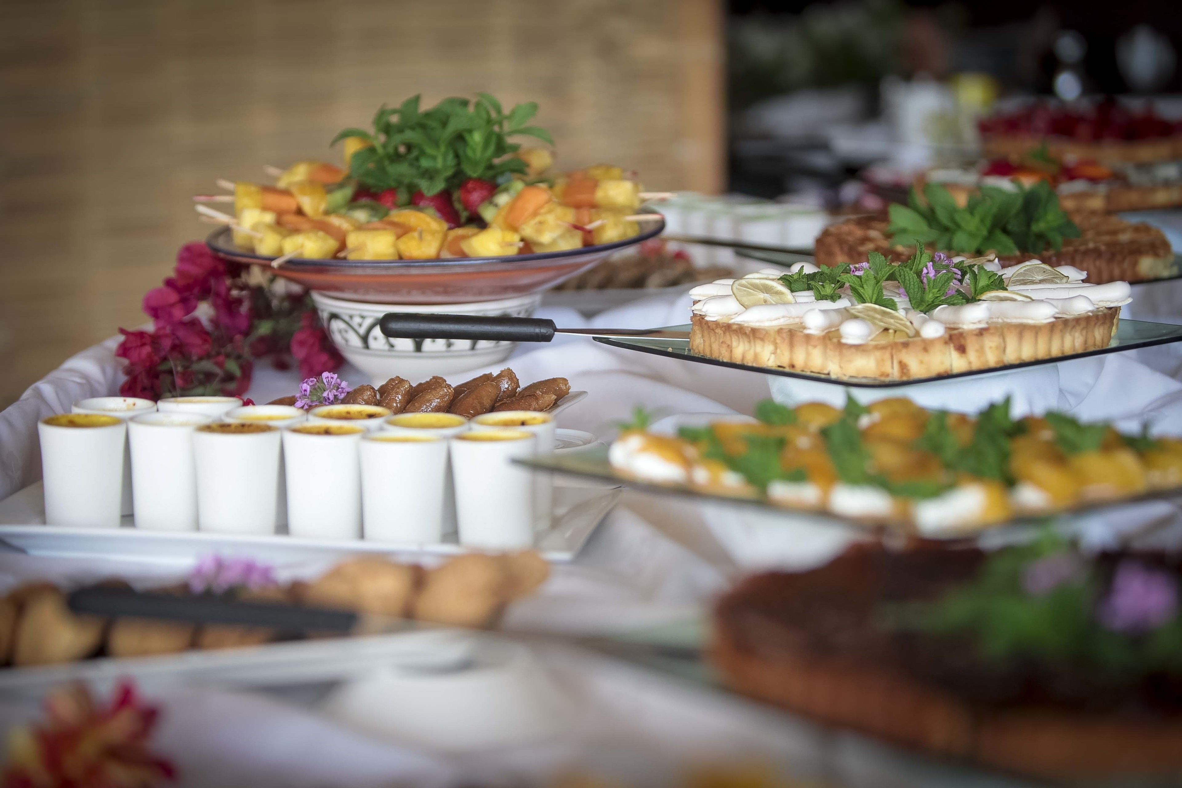 A buffet with various dishes, including fruit skewers, pastries, and a cake with mint and lemon slices.