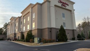 Ein Hampton Inn Hotel mit moderner Fassade, zahlreichen Fenstern und einem Parkplatz.