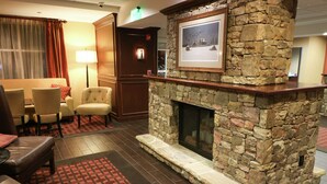 Eine Lobby mit Kamin aus Stein, Ledersitzmöbeln und einem gemusterten Teppich.