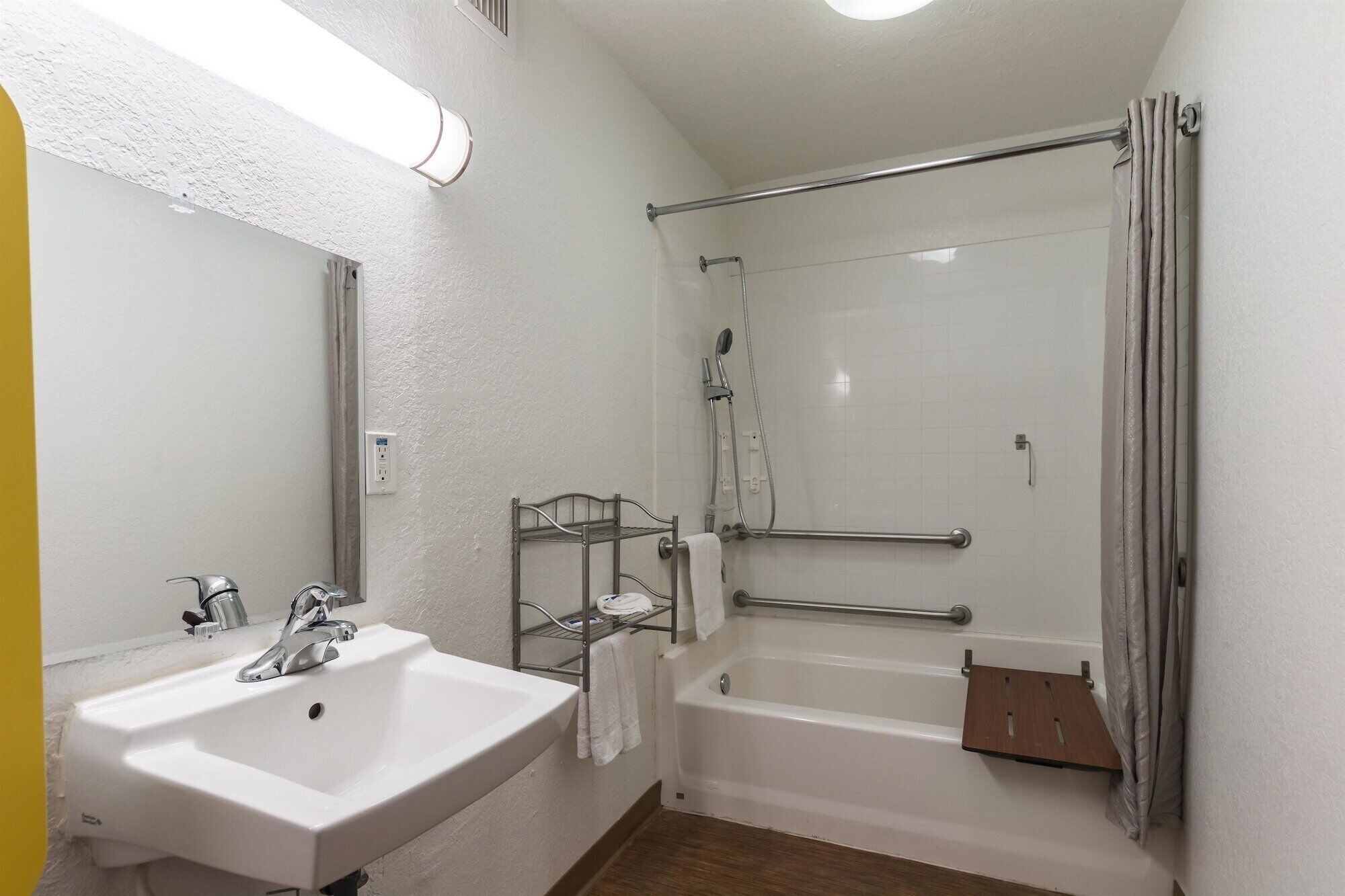 A bathroom with a white sink, a shower with a glass door, and a towel rack.