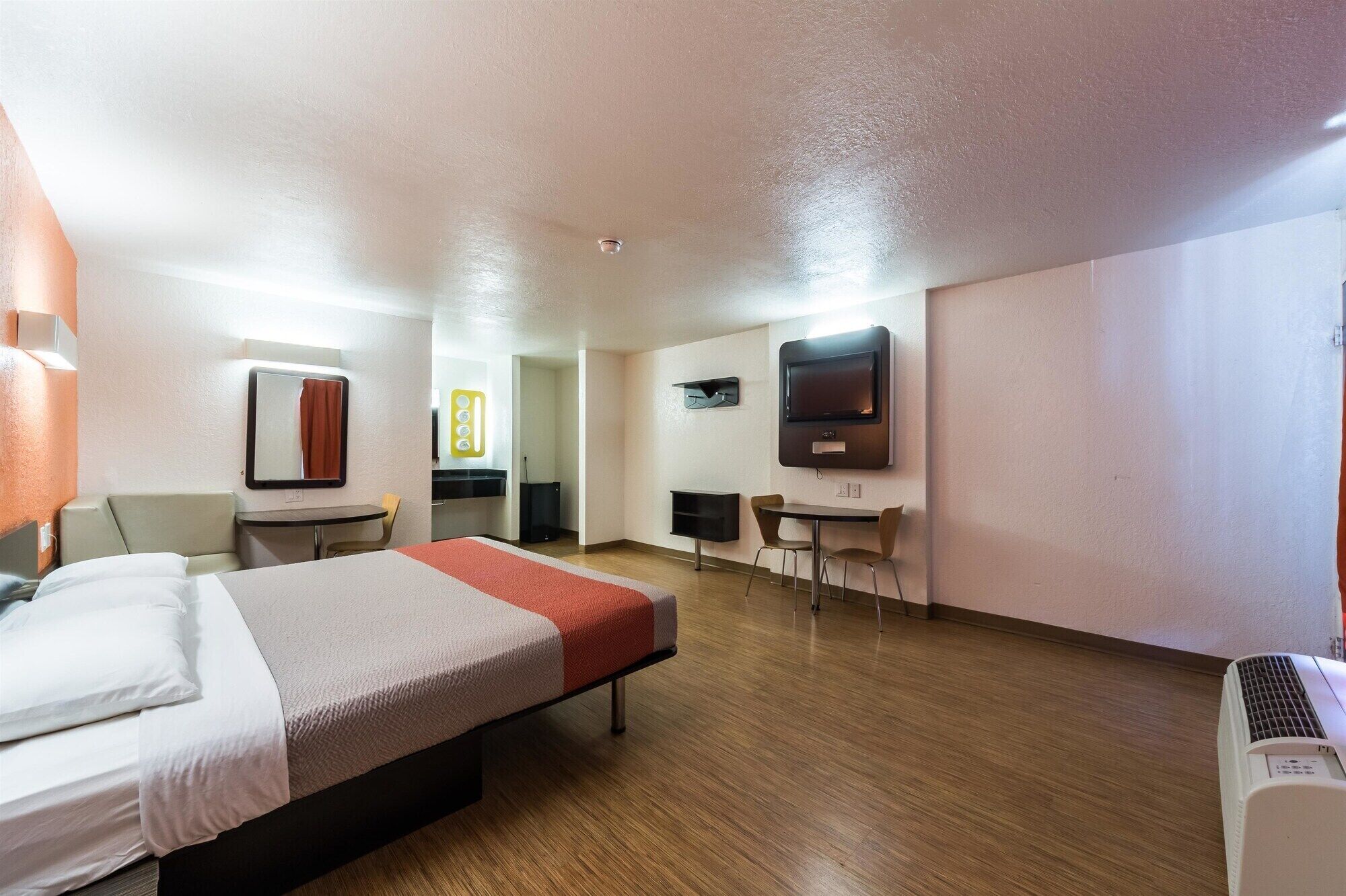 Habitación de hotel con cama, escritorio, silla, televisor y baño.