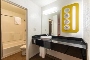 A modern bathroom with a black countertop, white sink, and a mirror with a yellow towel holder.