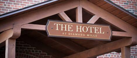 Un letrero de madera con el texto 'THE HOTEL AT DIAMOND MILLS'.