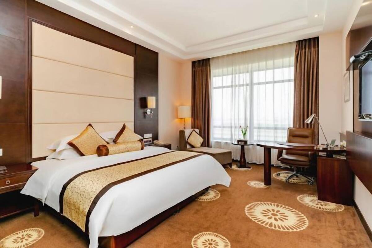 Habitación de hotel con una cama grande, un escritorio, una silla y un televisor.