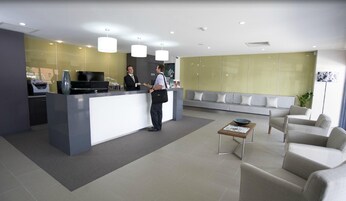 Un área de recepción moderna con mostrador, zona de estar y una mesa de centro.