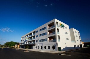 Un hotel moderno con diversi piani, balconi e una segnaletica ben visibile.