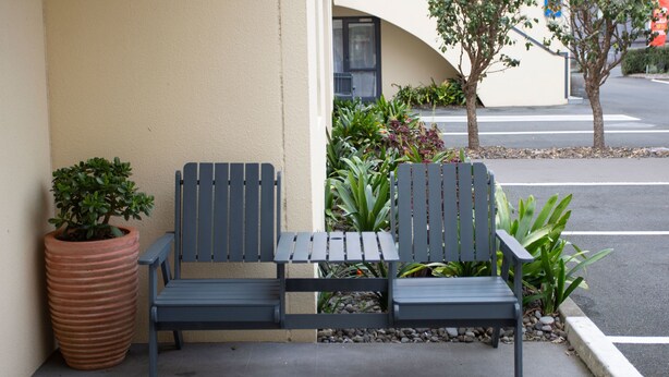 A bench with a planter and potted plant beside a building. - Bella Vista Motel New Plymouth (New Plymouth)