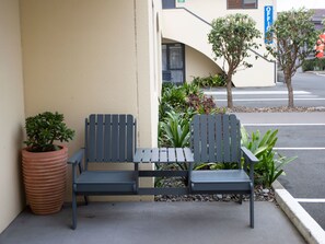 A bench with a planter and potted plant beside a building. - Bella Vista Motel New Plymouth (New Plymouth)