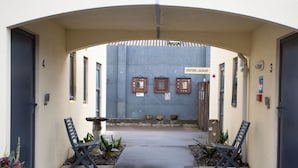 An entrance with a sign for visitors' laundry, a covered walkway, and two benches. - Bella Vista Motel New Plymouth (New Plymouth)