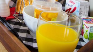 A breakfast tray with toast, juice, and a bowl of cereal on a checkered tablecloth. - Bella Vista Motel New Plymouth (New Plymouth)