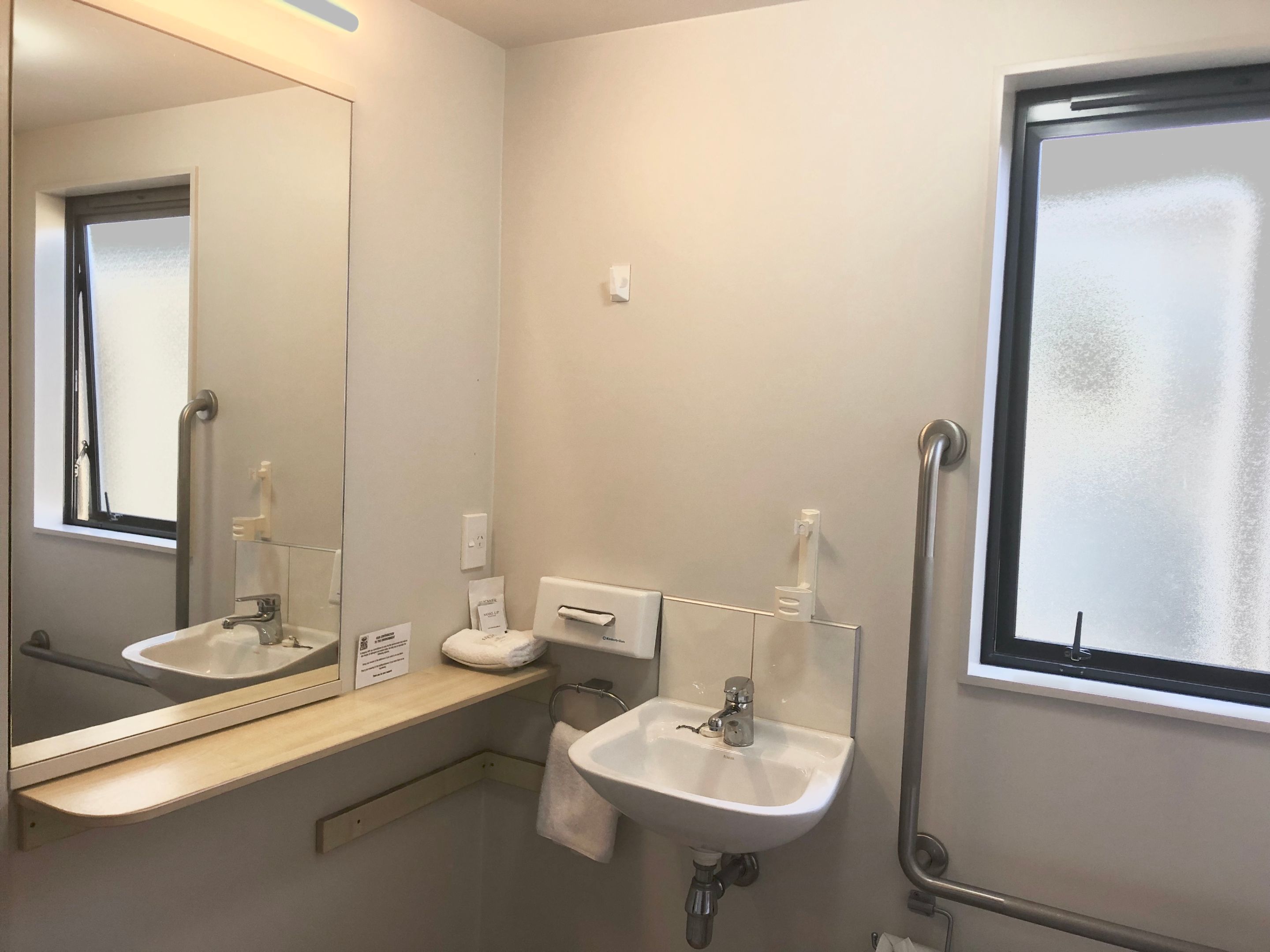 A bathroom with two sinks, a mirror, a towel rack, and a window.