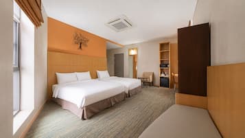 Ein Hotelzimmer mit zwei Betten, einem Schreibtisch, einem Stuhl, einem kleinen Tisch, einem Kleiderschrank und einer Wanddekoration.