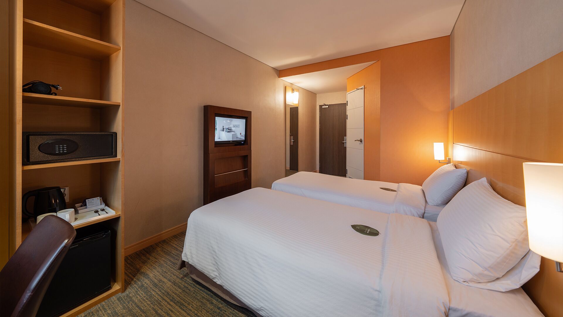 Une chambre d’hôtel équipée d’un lit, d’un bureau avec un ordinateur, d’une télévision et d’un mini-bar.