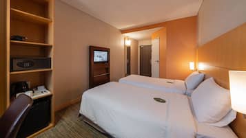 Une chambre d’hôtel équipée d’un lit, d’un bureau avec un ordinateur, d’une télévision et d’un mini-bar.