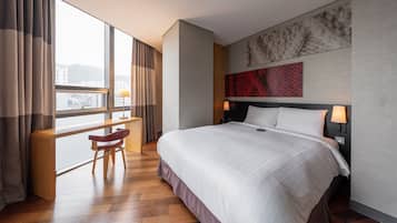 Habitación de hotel con una cama grande, un escritorio y una silla cerca de una ventana con cortinas.