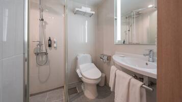Un baño moderno con cabina de ducha de vidrio, inodoro, lavabo y espejo.