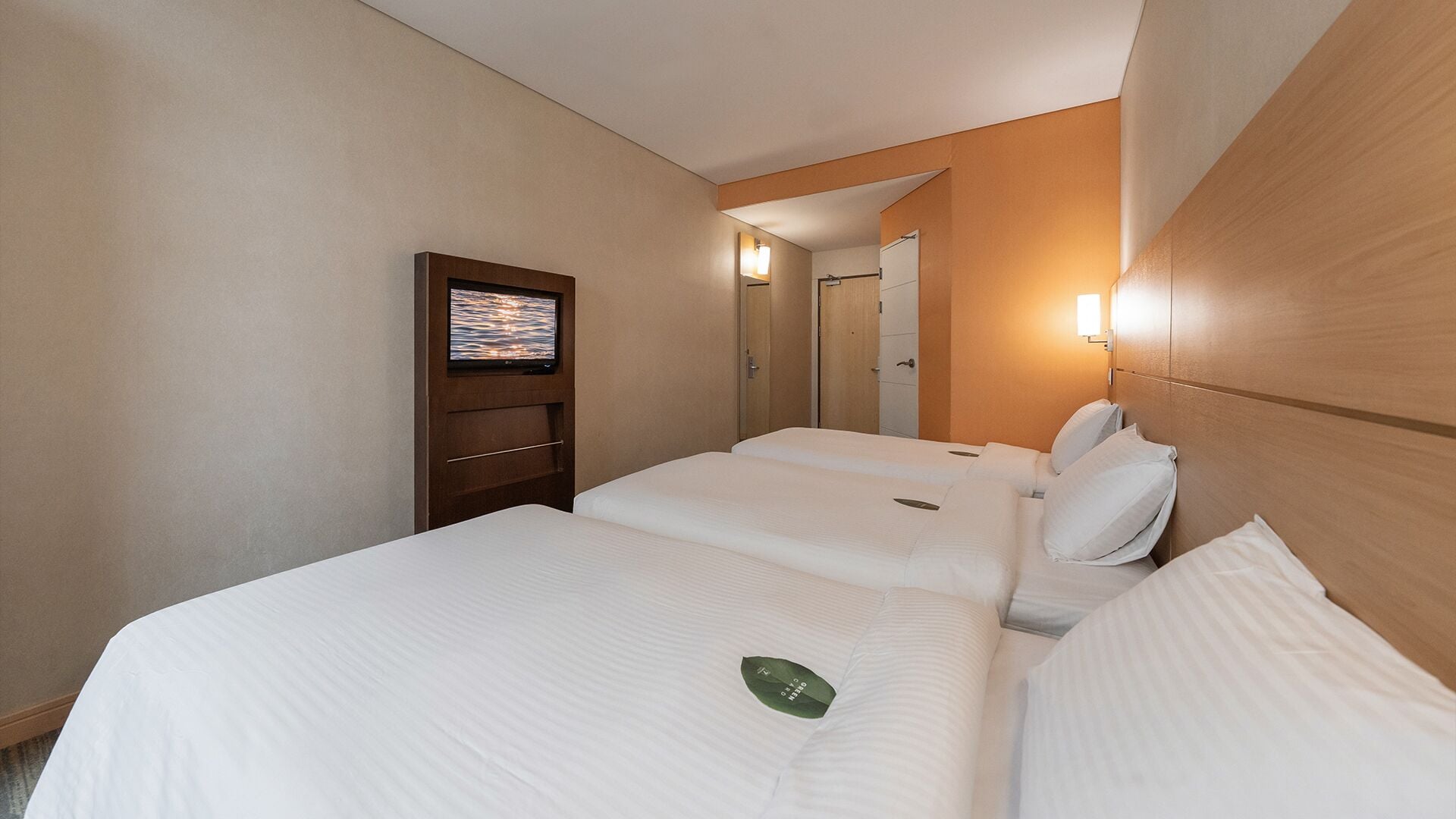 Een hotelkamer met twee bedden, een televisie aan de muur en een spiegel.