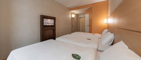 Een hotelkamer met twee bedden, een televisie aan de muur en een spiegel.