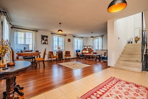 Un vaste salon doté d’un plancher en bois, un coin repas avec une table ronde et un escalier menant à l’étage supérieur.