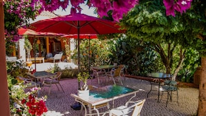Une terrasse extérieure avec une table et des chaises, entourée de plantes et de fleurs en pot.