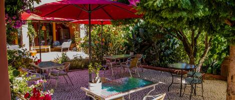 Un patio al aire libre con una mesa y sillas, rodeado de macetas con plantas y flores.