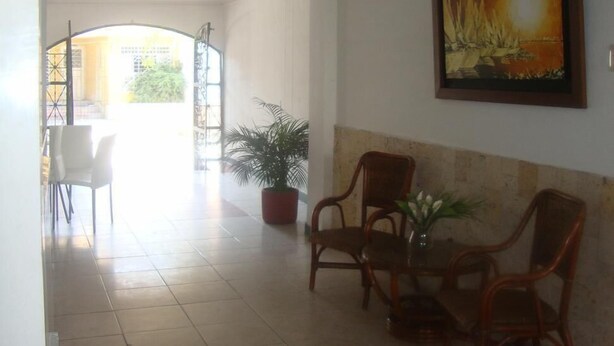 A spacious hallway with a dining area, a potted plant, and a framed painting on the wall. - Ayenda 1614 Playa y Mar (Santa Marta)