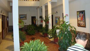 A spacious indoor area with multiple potted plants, a staircase, and a painting on the wall. - Ayenda 1614 Playa y Mar (Santa Marta)