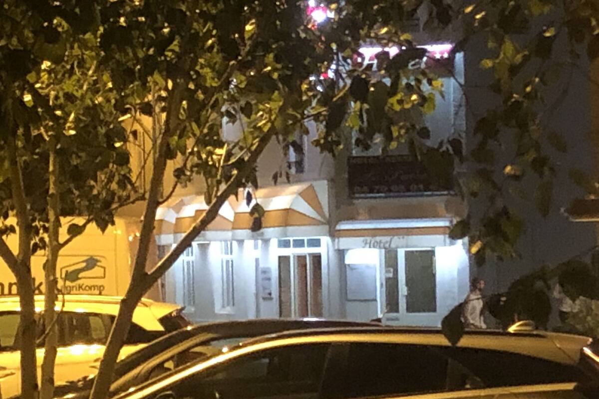 Un bâtiment avec une enseigne indiquant « Hôtel » et une voiture garée devant.
