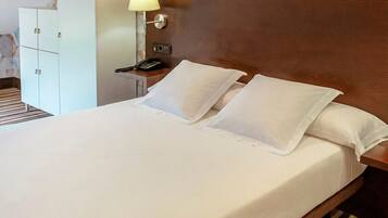 A hotel room with a bed, a nightstand, a lamp, a wardrobe, and a wall-mounted picture.